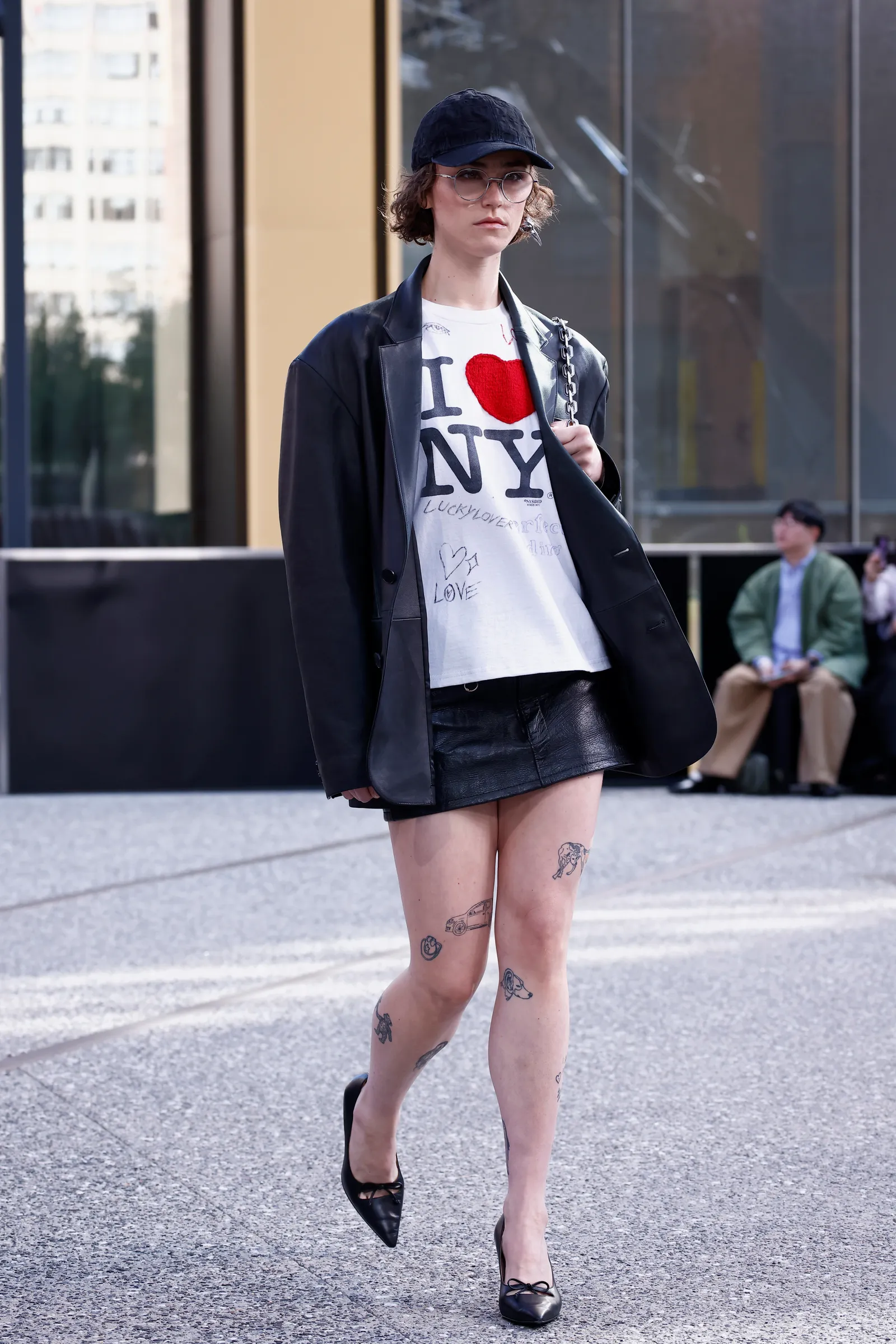 A person wearing an &quot;I Love NY&quot; T-shirt and leather jacket walks on a runway.