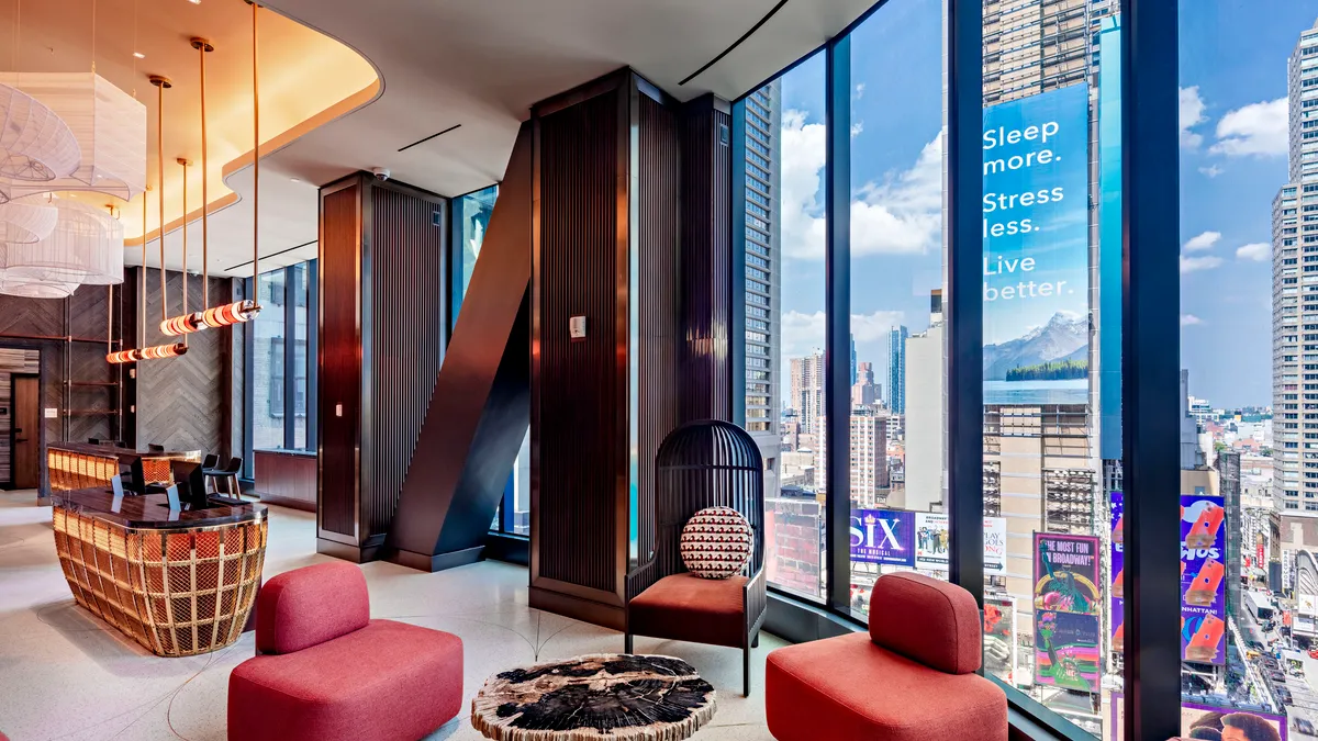 Red armchairs in Tempo by Hilton's lobby, which has floor-to-ceiling windows with views of Times Square