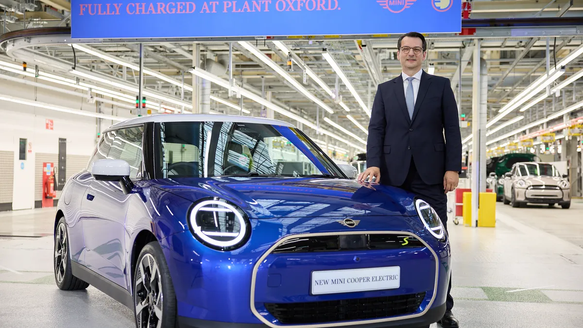 Dr Milan Nedeljković, Member of the Board of Management of BMW AG, poses with a blue MINI Cooper Electric at the Oxford plant.