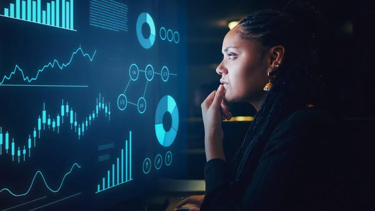 A woman analyzing graphs displayed on a computer screen, focused on data interpretation and insights.