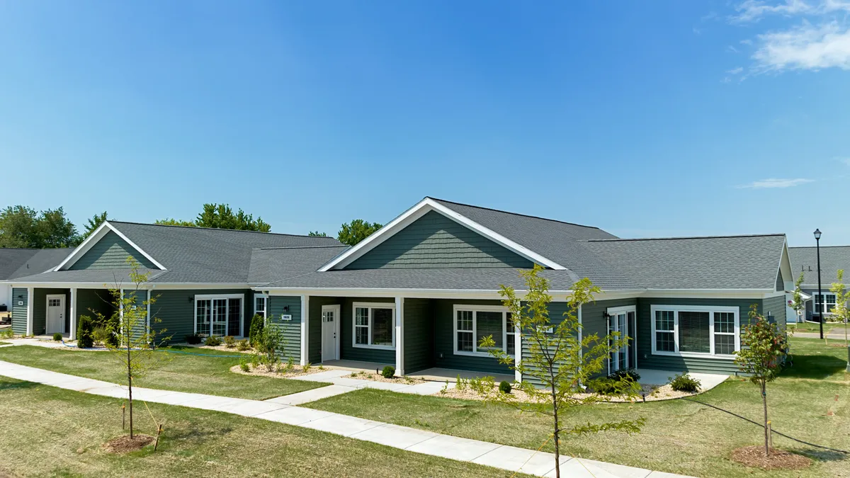 A row of single-story attached homes with green siding.