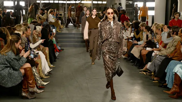 Models walk the runway as people watch.