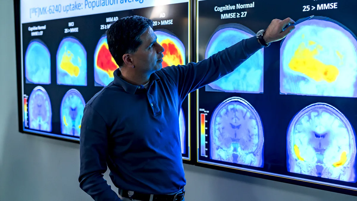 Ajay Purohit, a Biogen employee, points to brain scans of people with Alzheimer's