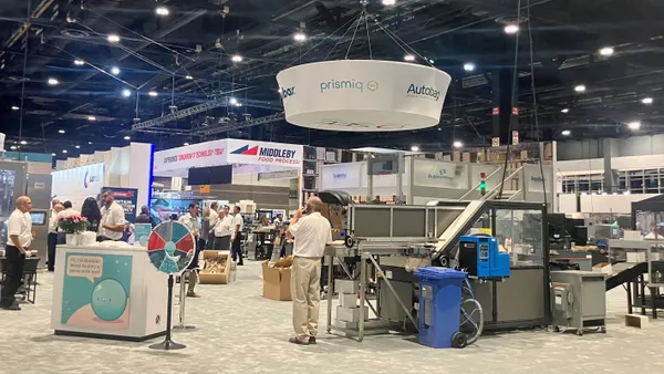 A wide shot of Sealed Air's exhibiting area on the show floor of Pack Expo International, with people and machinery throughout