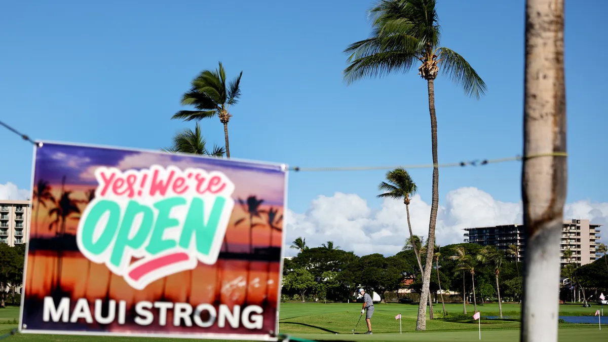 A sign reading "Yes, we're open!" is seen at a golf course.