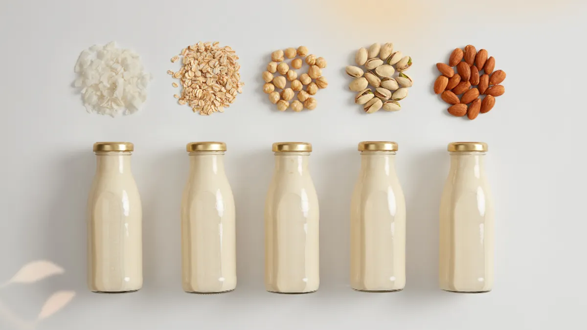 Bottles of plant-based milks next to their main ingredient.