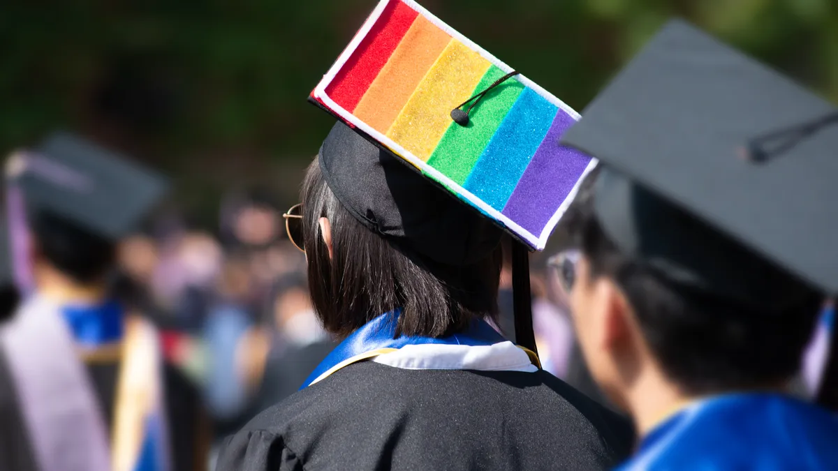 A woman wears a mortar board customized with a LGBT pride rainbow flag.