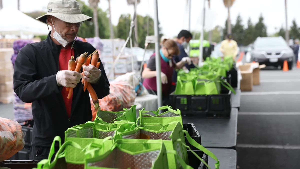 Individuals pack food into bags lined up on tables.