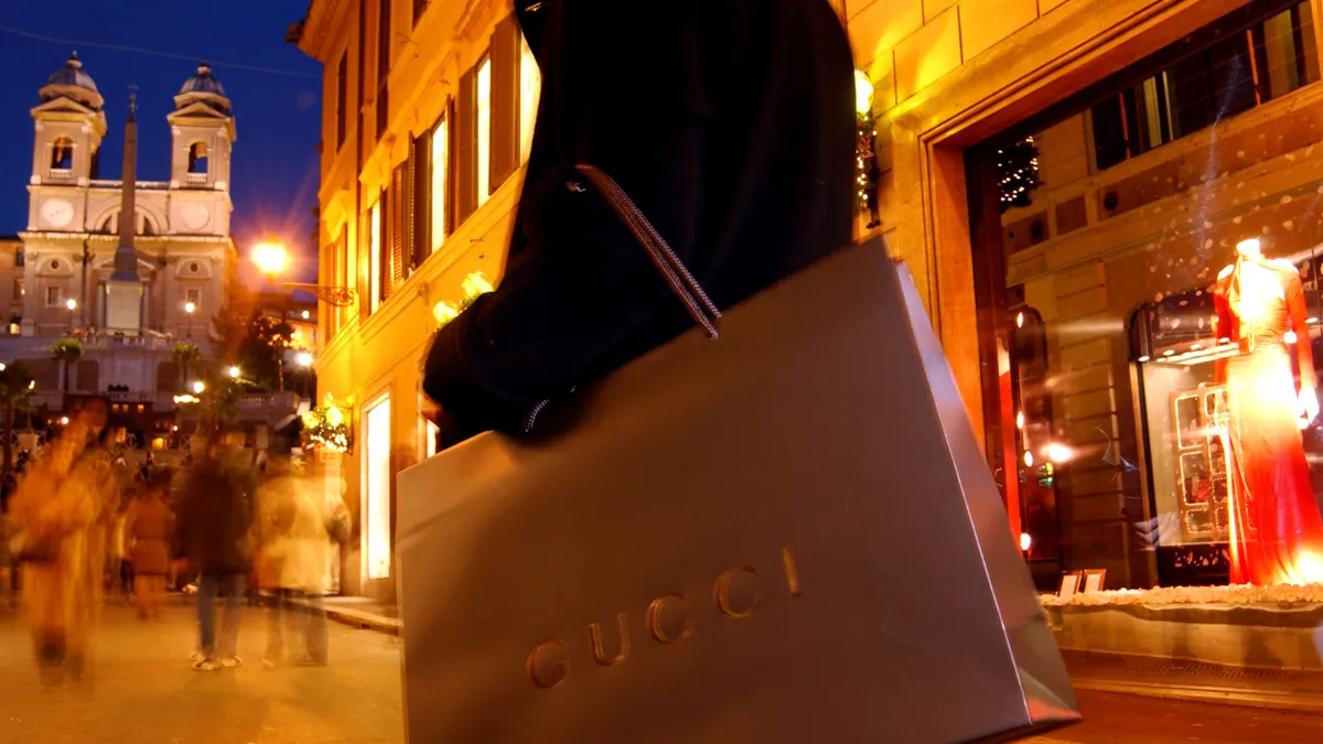 A closeup of a person with Gucci shopping bag in the twilight on a street in Rome, Italy.