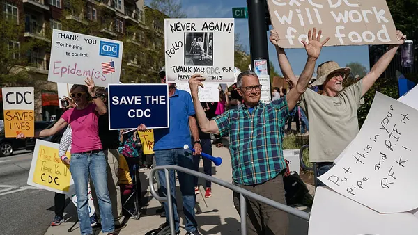A group of protestors hold signs outside the CDC's campus.