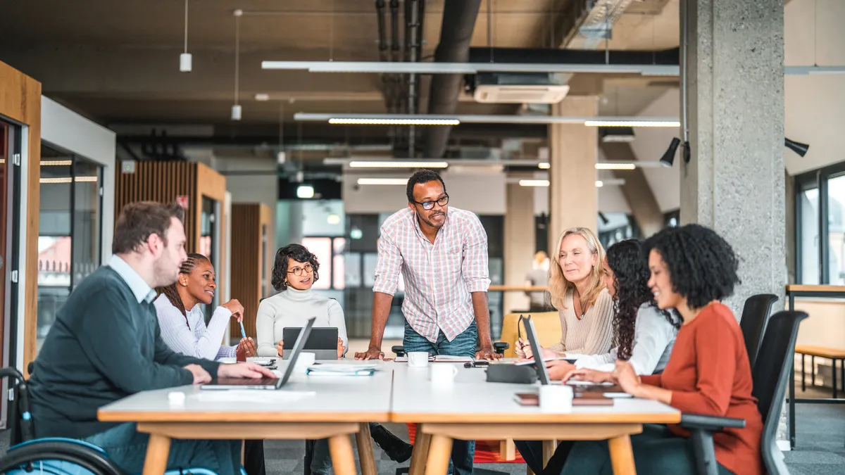 A group of workers sit around an office desk.