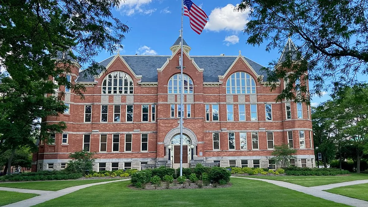 Large brick building with turrets on St. Norbert campus with flagpole at center of frame.