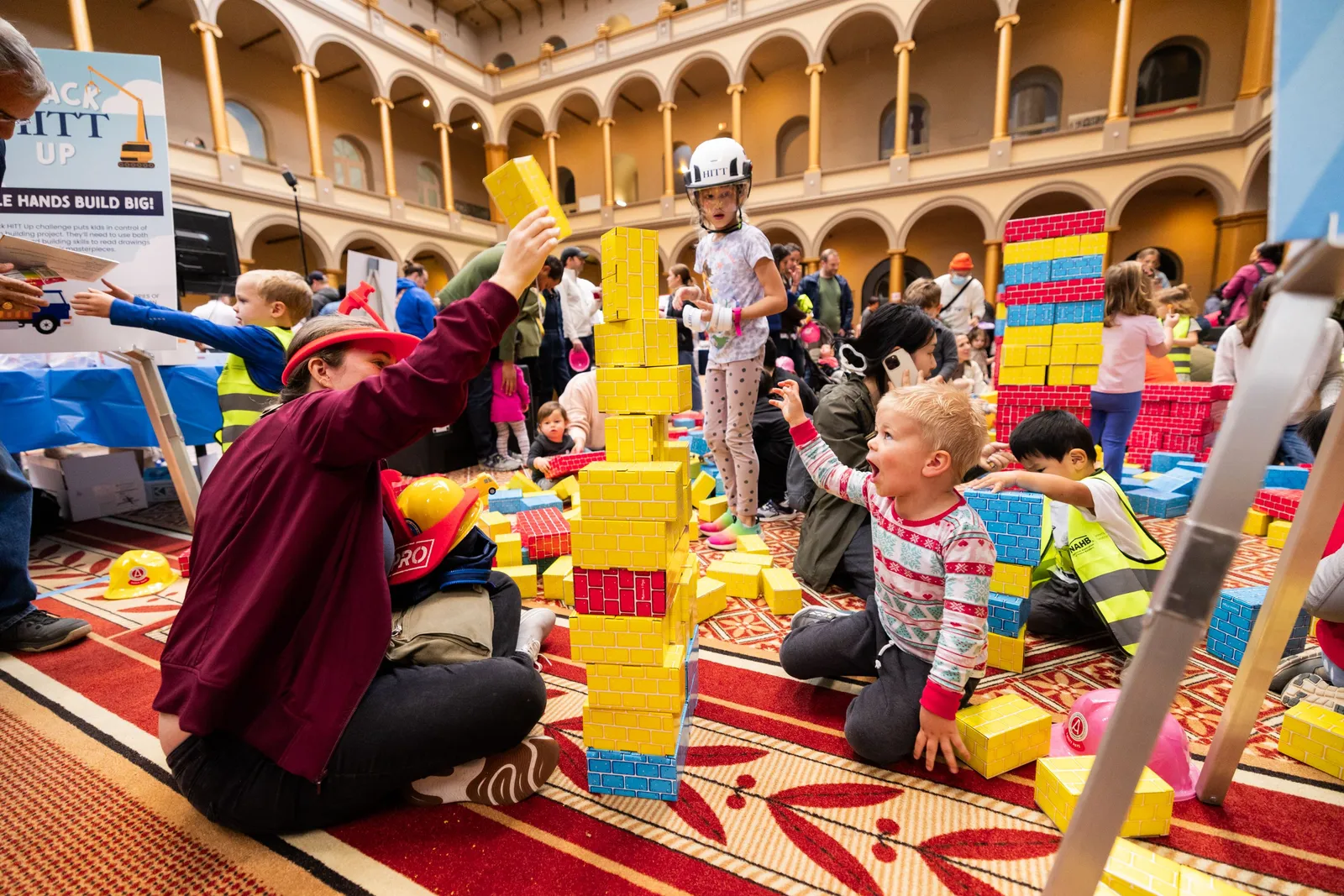 Several children build structures with toy blocks on the floor.