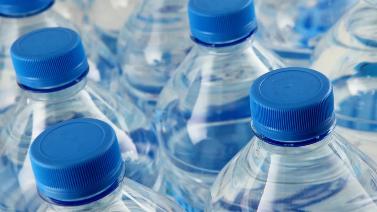 The capped tops of blue plastic water bottles