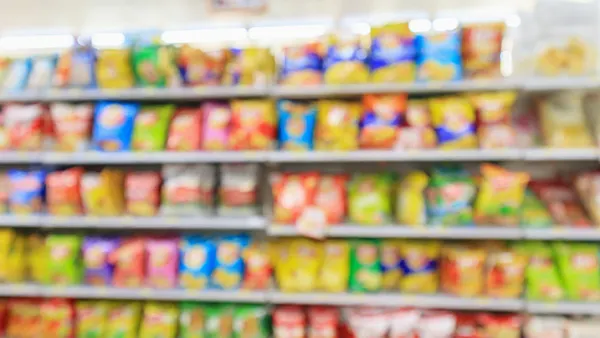 Blurred view of chip packages arranged on store shelves, creating a colorful display.