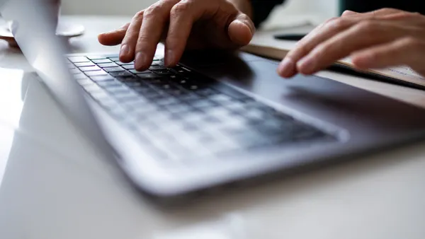 close up of a man typing on a laptop