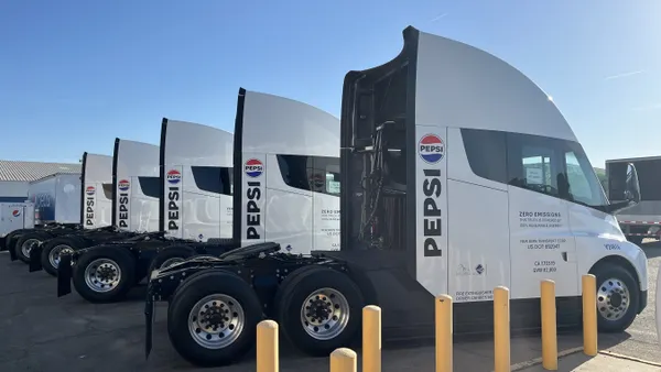 Five trucks with the Pepsi logo parked.