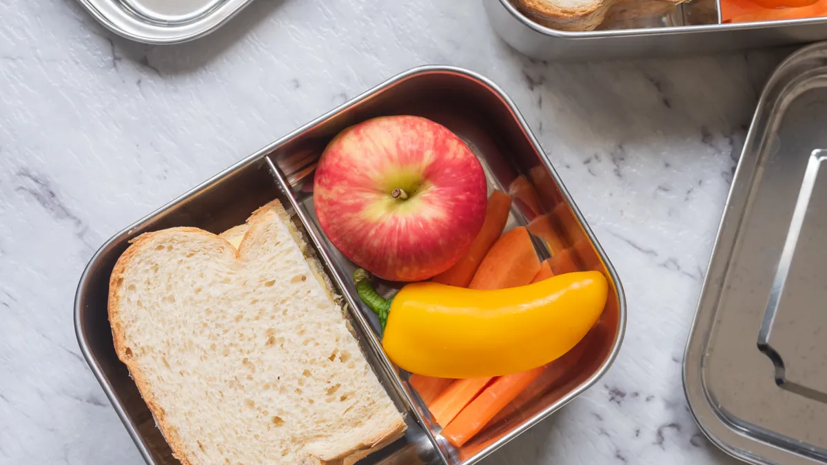 A metal reusable food container filled with lunch foods