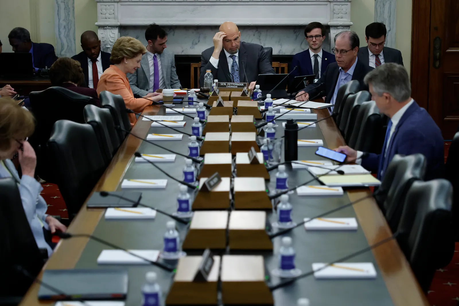 A table of politicians. Sen. John Fetterman sits at the head of the table with a hand on his forehead.