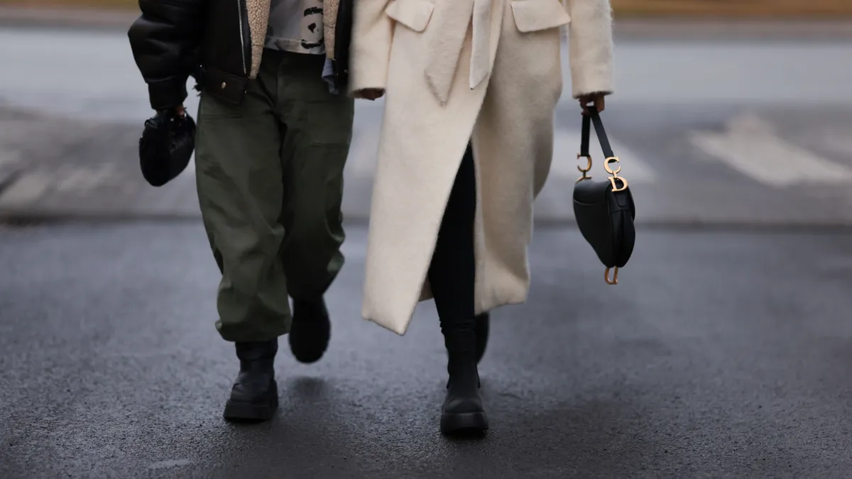 Two people walk side by side down the street wearing coats.