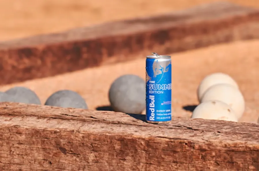 A photo of a can of Red Bull on a piece of wood.