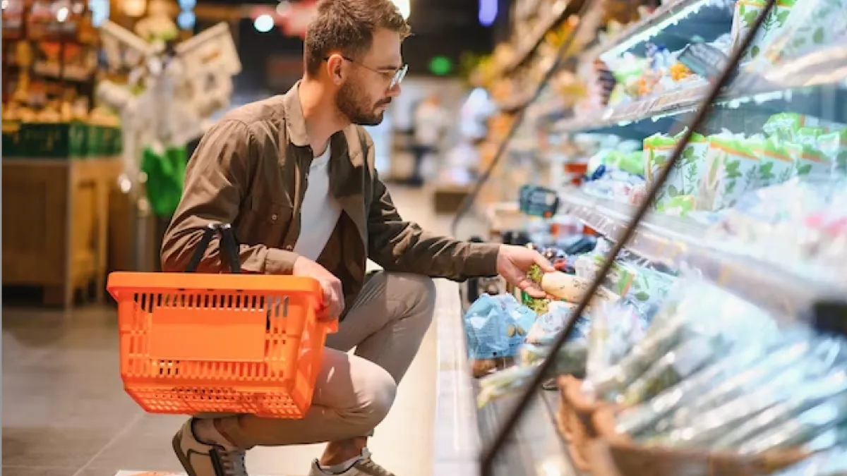 Man with orange basket shopping for produce in a grocery store