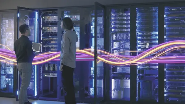 2 people standing in front of a lot of computer servers.