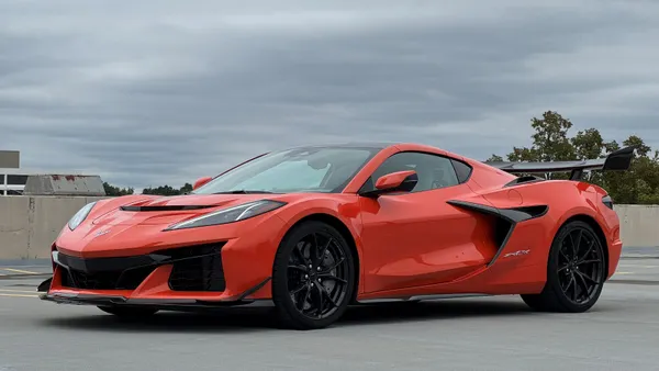 An orange Chevrolet Corvette ZR1X stands in a parking lot under gray skies.