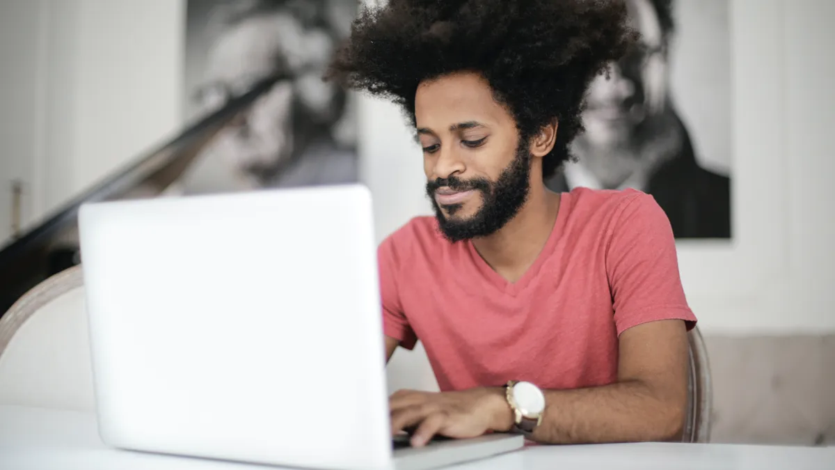 man in red shirt using a laptop