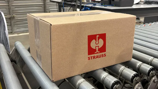 A Strauss-branded box sits on a conveyer belt