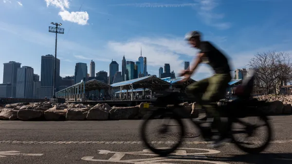 A blurred rider on a bicycle with tall buildings in the background.