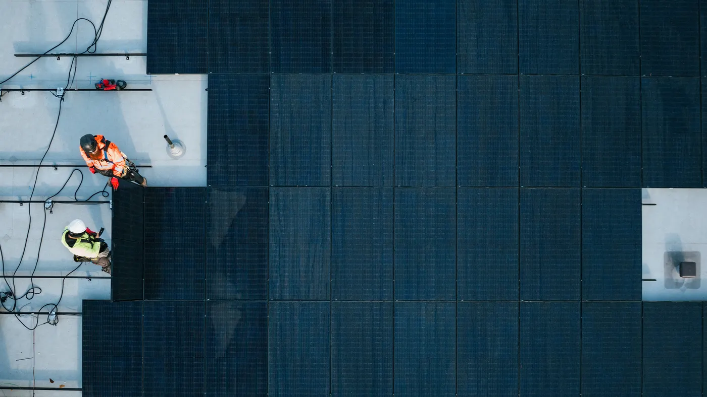 A group of solar panel installers work on a roof.
