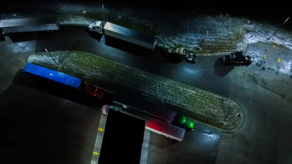 A truck stop at night shown from overhead with lights shining on parts of equipment.