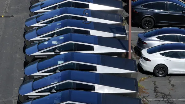 In an aerial view, brand new Tesla Cybertrucks sit parked in a lot at a Tesla dealership on April 02, 2025 in Corte Madera, California. E