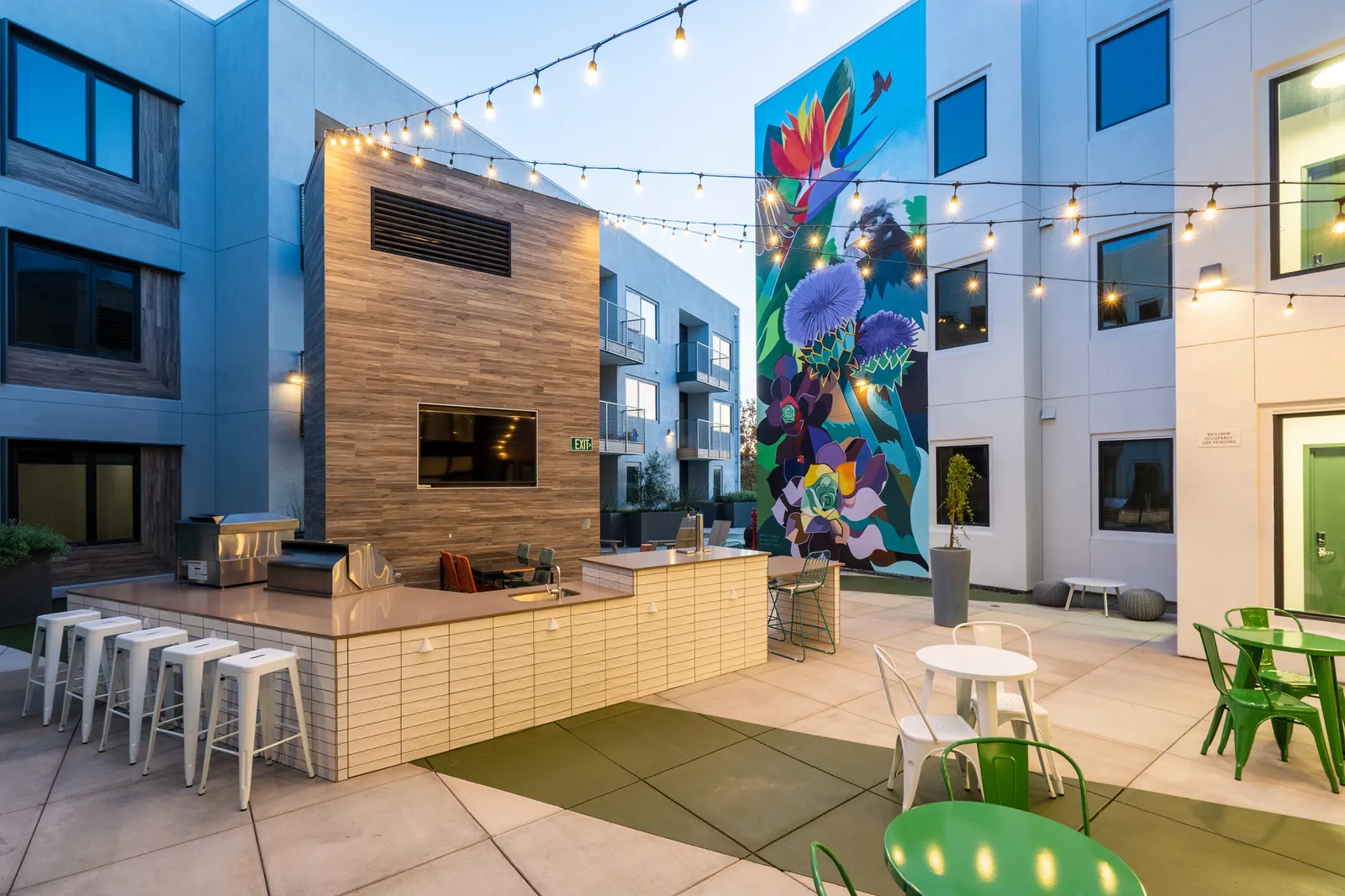 A patio at an apartment building with a colorful mural and bar counter.