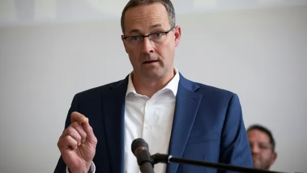 A person in a suit gesturing while speaking.