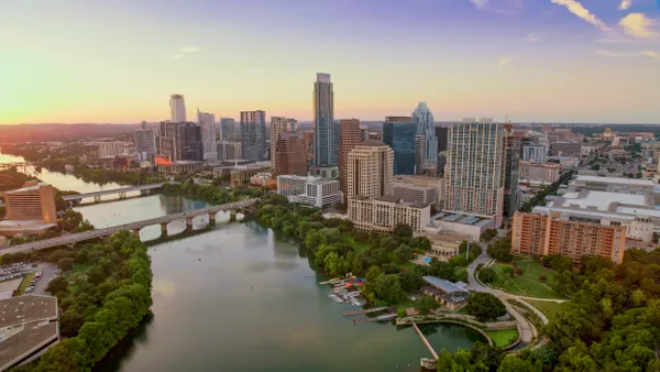 Aerial view of a wide river crossed by several small bridges with tall downtown buildings on one side.