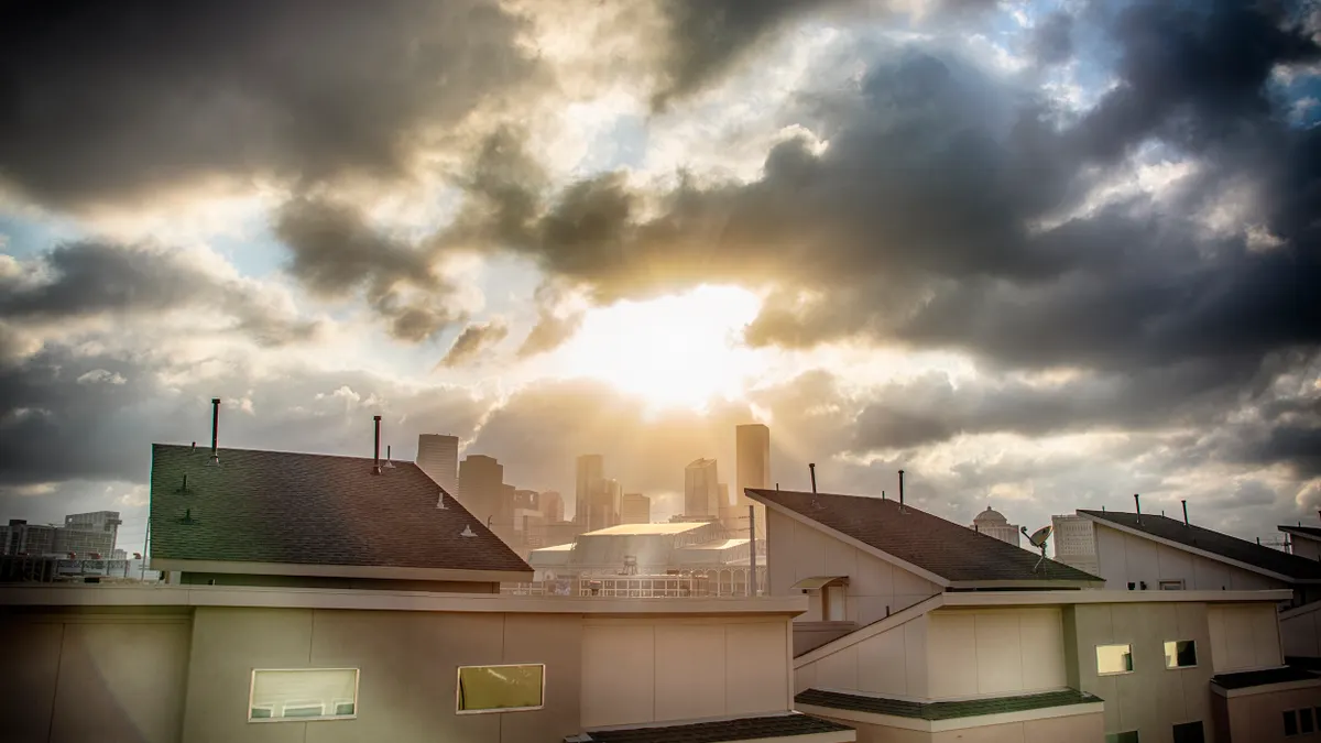 Homes in foreground, clouds clearing over skyline in the background.