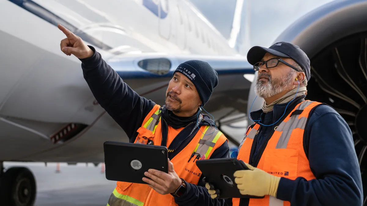 Two United Airlines employees using iPads on the job