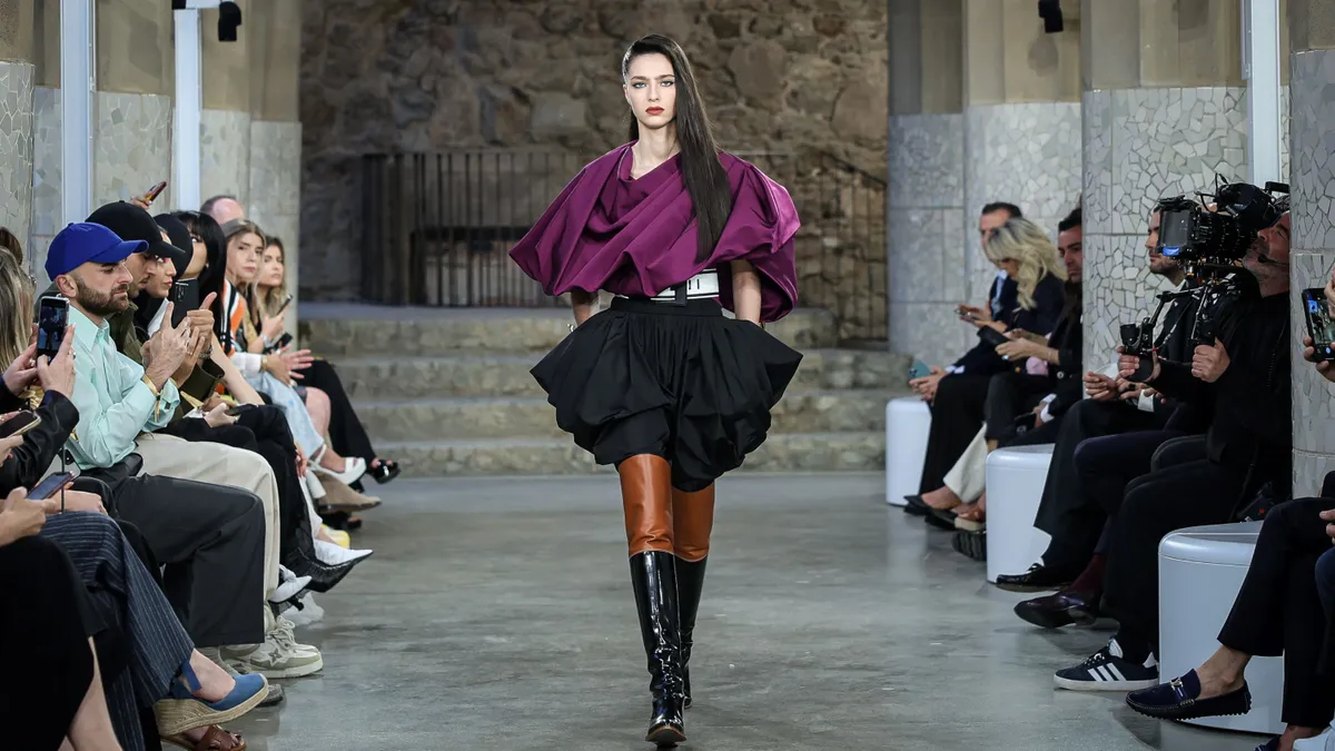 A model in a pouf skirt walks down a runway.