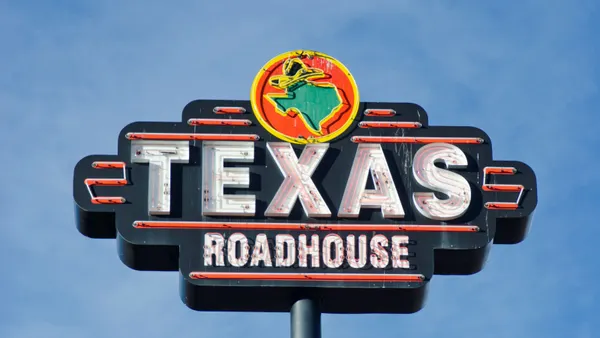 A large sign that says Texas Roadhouse in front of a blue sky.