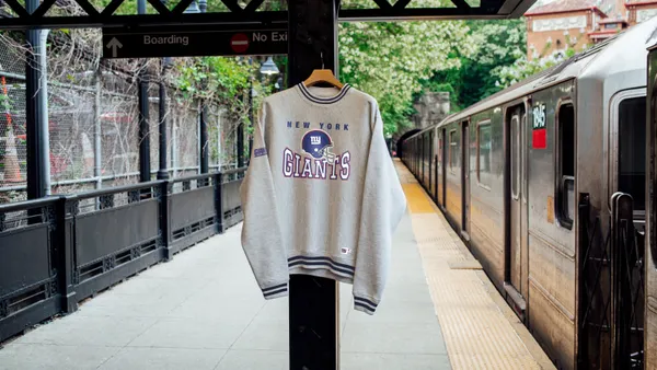 A sweatshirt featuring the logo of the NY Giants hangs from a column at an outdoor subway stop in New York.