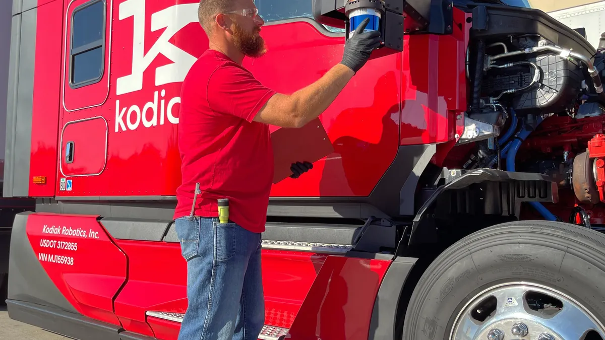 A Kodiak Robotics staffer stands next to and inspects an autonomous truck.