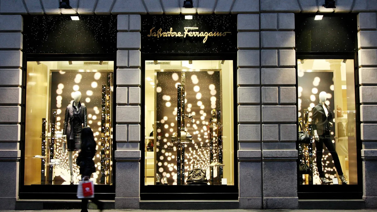 A shopper walks in the evening past a lighted store window of a Salvatore Ferragamo boutique in Milan.