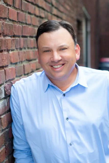 A person in a blue shirt smiles at the camera