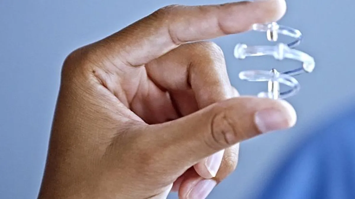 Close up of a hand holding a spiral, plastic device with metal spurs.