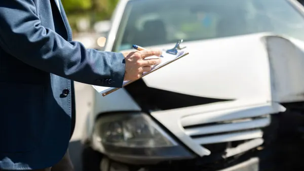 Agent from the insurance company checking a car for damage after a road mishap.