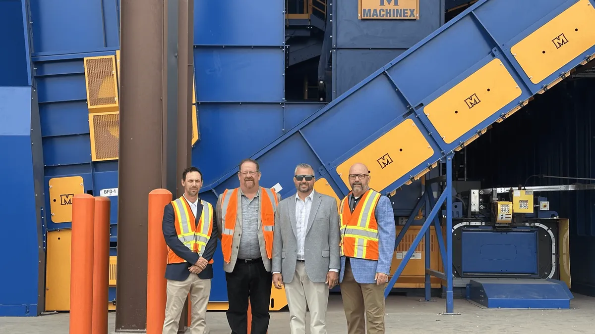 Employees stand in front of a MRF