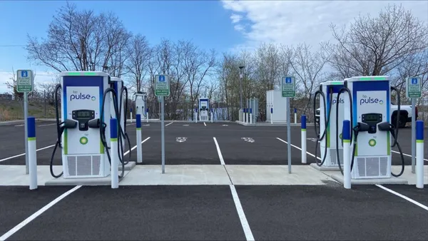 A photo of a parking lot with a number of EV chargers set up alongside the parking spaces.