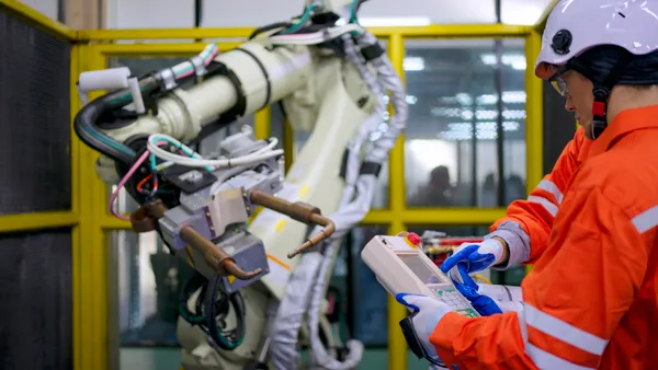 Two technicians work with a robotic arm.